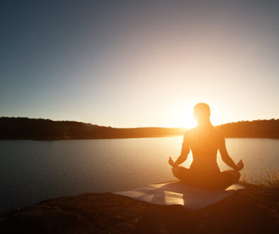 Silhouette of healthy woman is practicing yoga at mountain lake