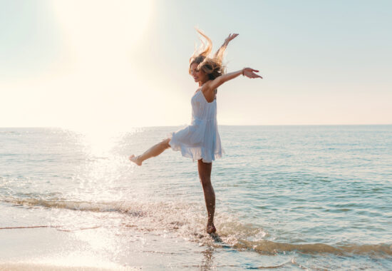 young attractive happy woman dancing turning around by sea beach sunny summer fashion style scaled 550x380 - Blog